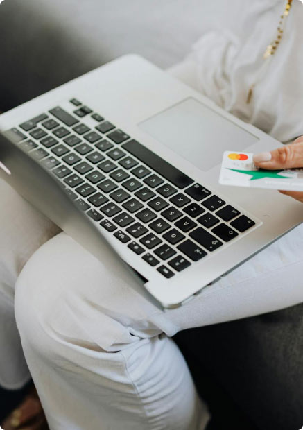 A lady using a debit card to make a purchase on a laptop computer